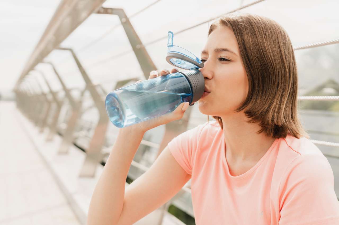 Mädchen das Wasser aus einer Flasche trinkt.